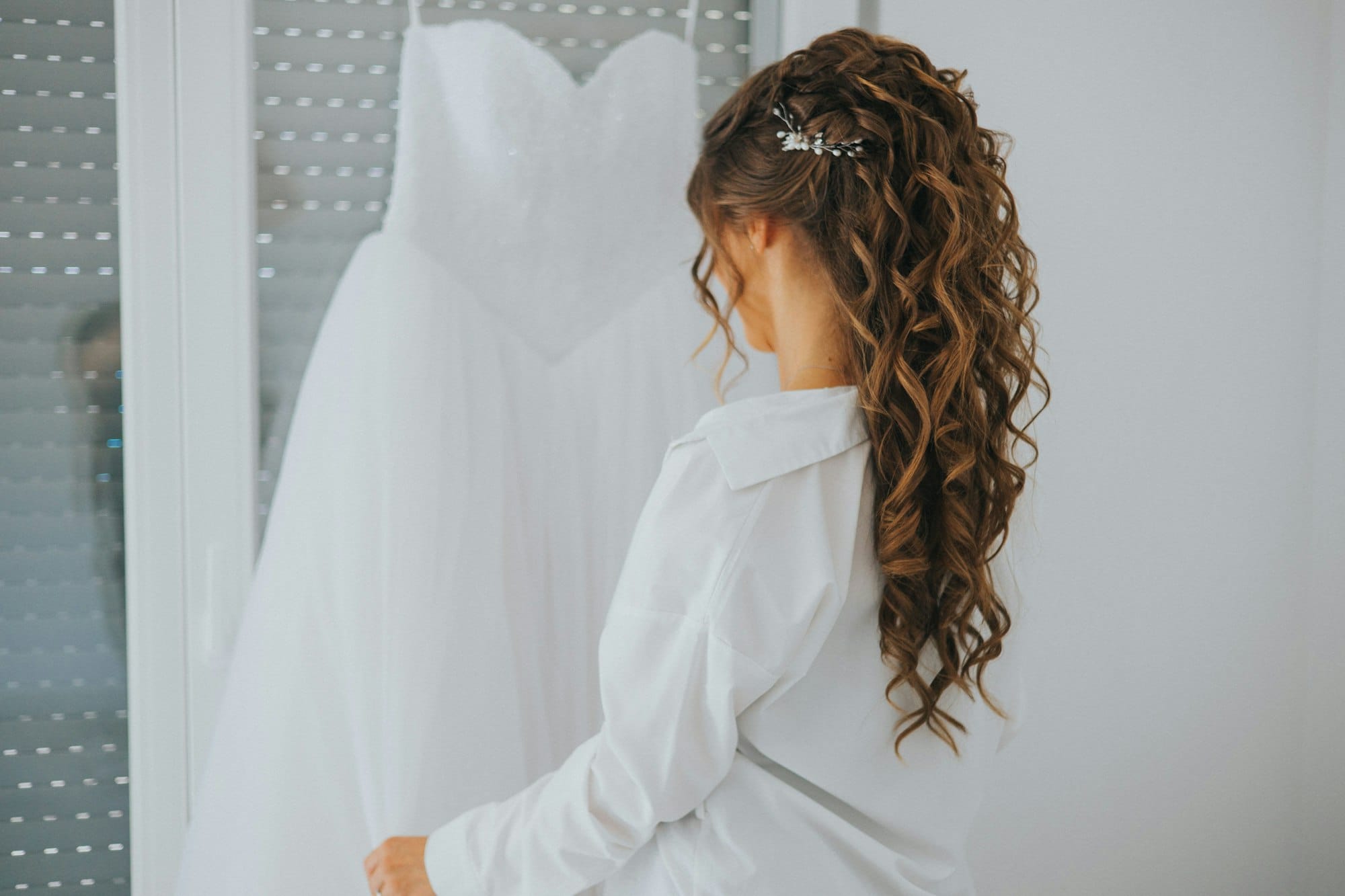 Bride with beautiful hair observing her bridal dress on her wedding day